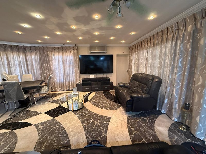 Spacious living area featuring recessed downlighting, split-system air conditioning, and decorative coving, currently showing signs of ceiling water damage.