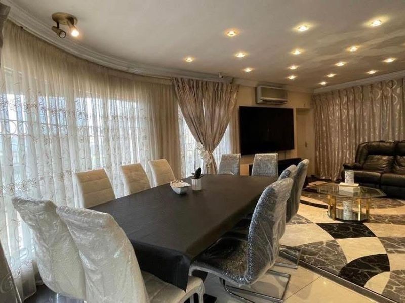 Spacious open-plan living and dining area featuring tiled flooring, recessed downlighting, and an integrated air conditioning unit.