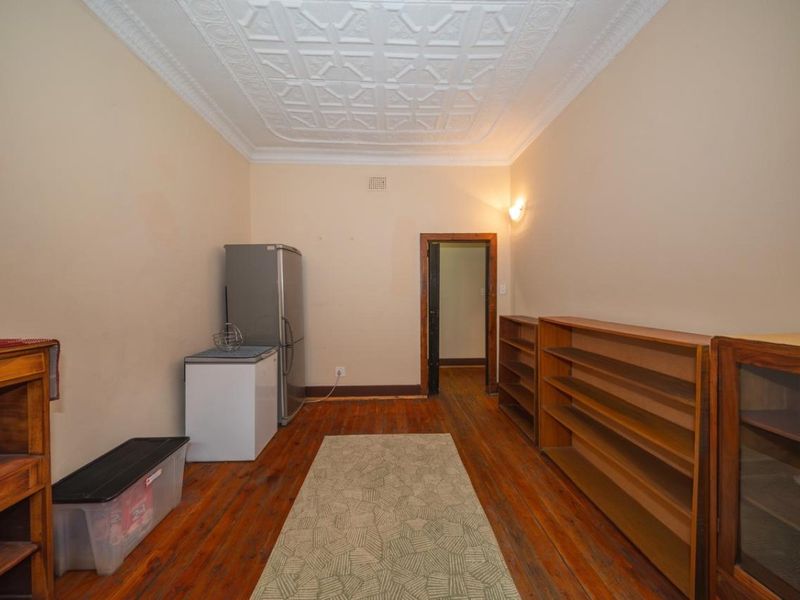 A utility space featuring original timber flooring and a decorative pressed metal ceiling, offering potential for a functional storage or multi-purpose room.