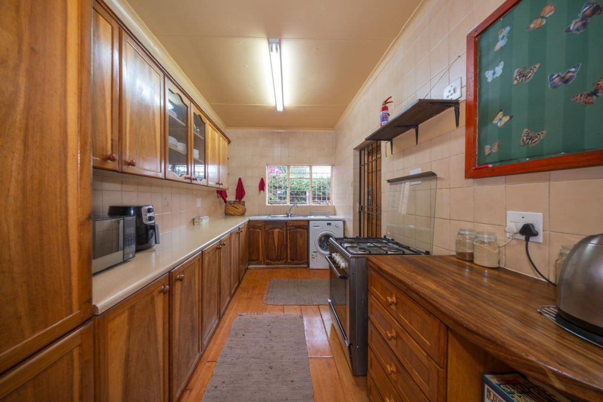 A functional kitchen featuring extensive wooden cabinetry, laminate countertops, a gas stove, and tiled splashbacks, offering a traditional layout with ample storage space.