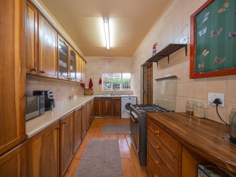 A functional kitchen featuring extensive wooden cabinetry, laminate countertops, a gas stove, and tiled splashbacks, offering a traditional layout with ample storage space.