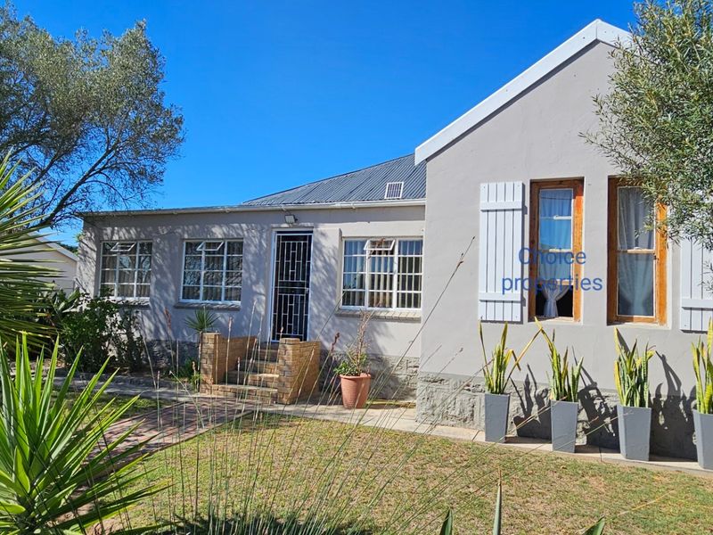 Front elevation of a charming house featuring a metal roof, timber window frames with shutters, and a brick entrance step.