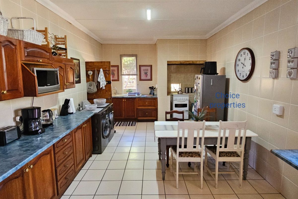 A functional kitchen featuring wooden cabinetry, tiled walls and flooring, and a dedicated dining area, offering a practical layout for daily use.
