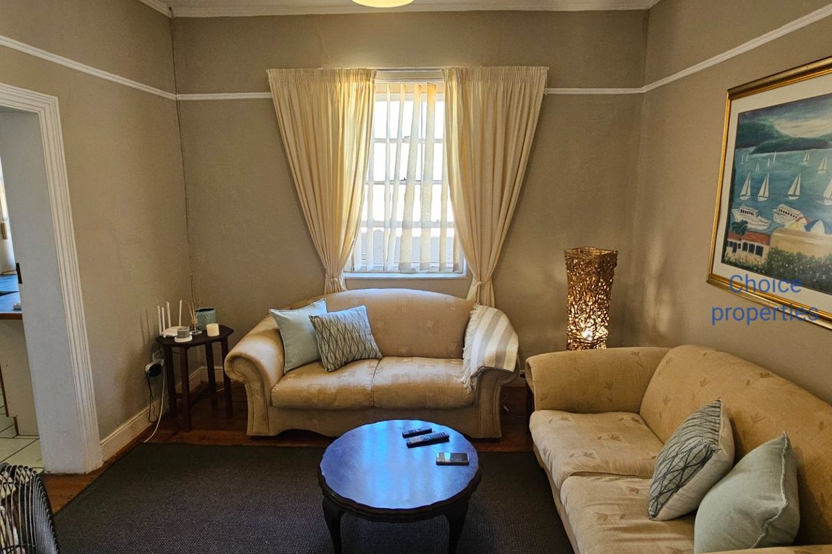 A cozy living room featuring classic picture rails and neutral wall tones, providing a comfortable space with direct access to the adjacent kitchen area.