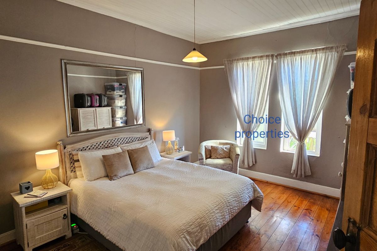 A cozy bedroom featuring warm timber flooring, a classic picture rail, and a traditional tongue and groove ceiling.