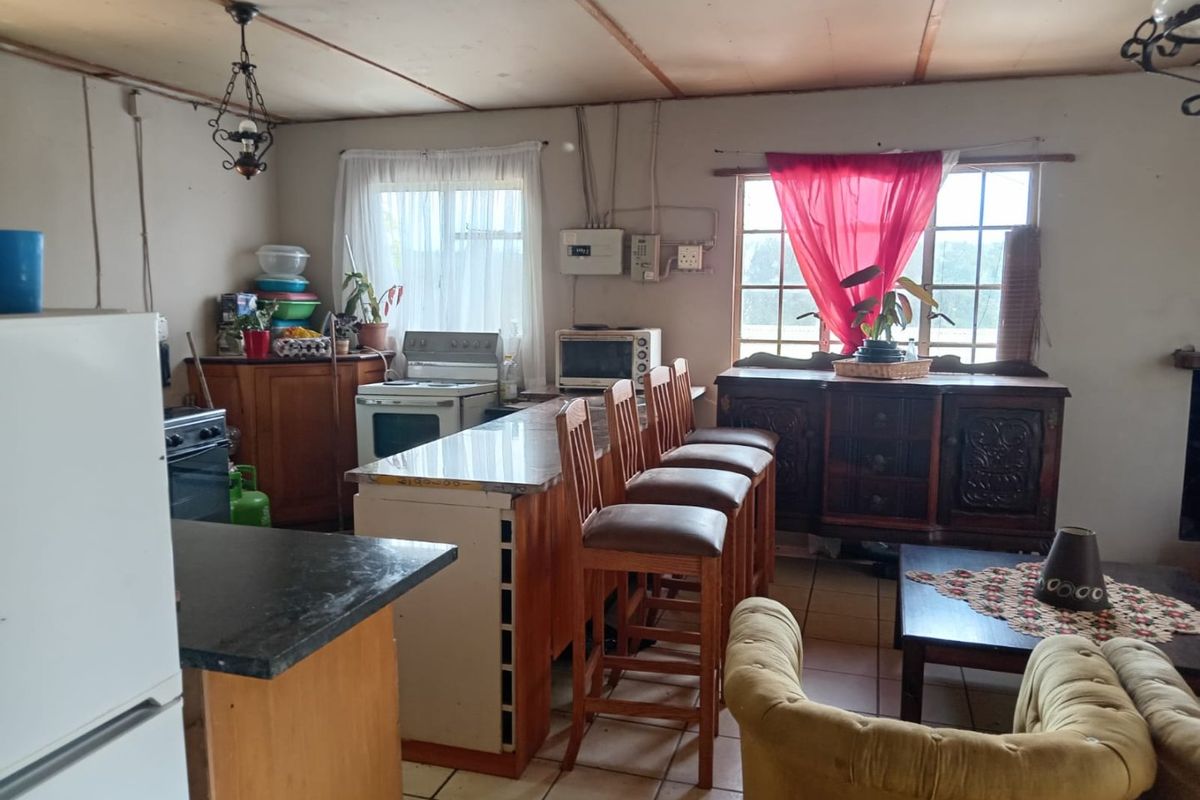 Open-plan kitchen and living area featuring a central island, tiled flooring, and exposed ceiling beams, offering potential for modernization and layout optimization.