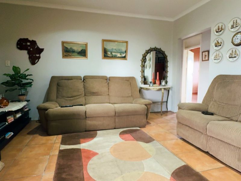 A comfortable living room featuring ceramic tile flooring and coved ceiling cornices, providing a functional and well-maintained space for relaxation.