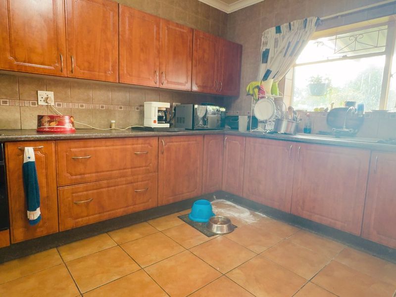 Functional kitchen featuring wooden cabinetry, tiled backsplash, built-in oven, and hob, with direct access to the rear garden area.