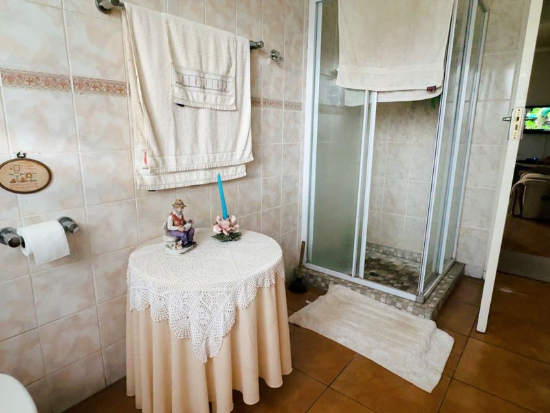 A functional bathroom featuring a corner shower enclosure, tiled wall finishes, and ceramic floor tiling.