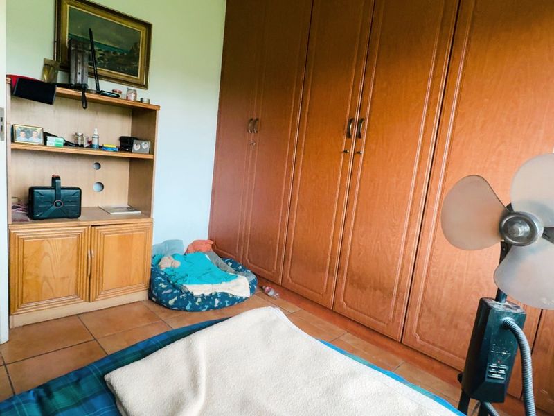 A bedroom featuring built-in wooden cupboards and tiled flooring, offering functional storage space.