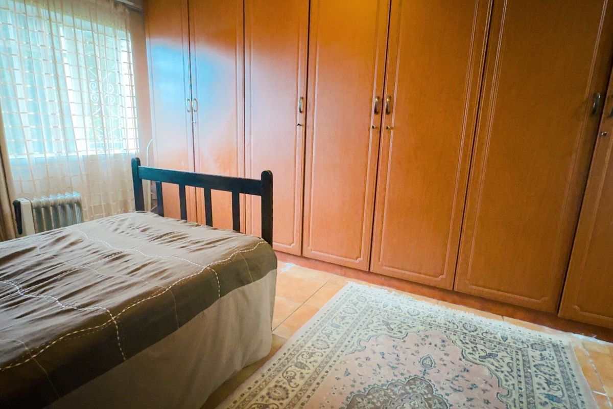A bedroom featuring extensive built-in wooden cupboards and tiled flooring, offering ample storage space.