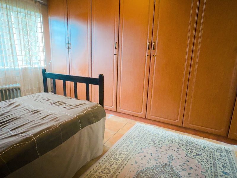 A bedroom featuring extensive built-in wooden cupboards and tiled flooring, offering ample storage space.