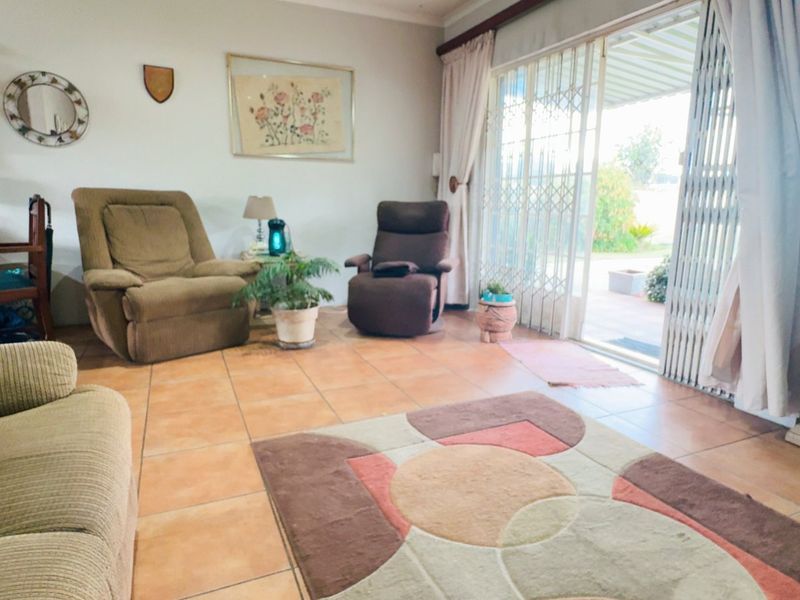 Spacious living room featuring tiled flooring and a large sliding glass door with security gate, providing direct access to the outdoor patio area.
