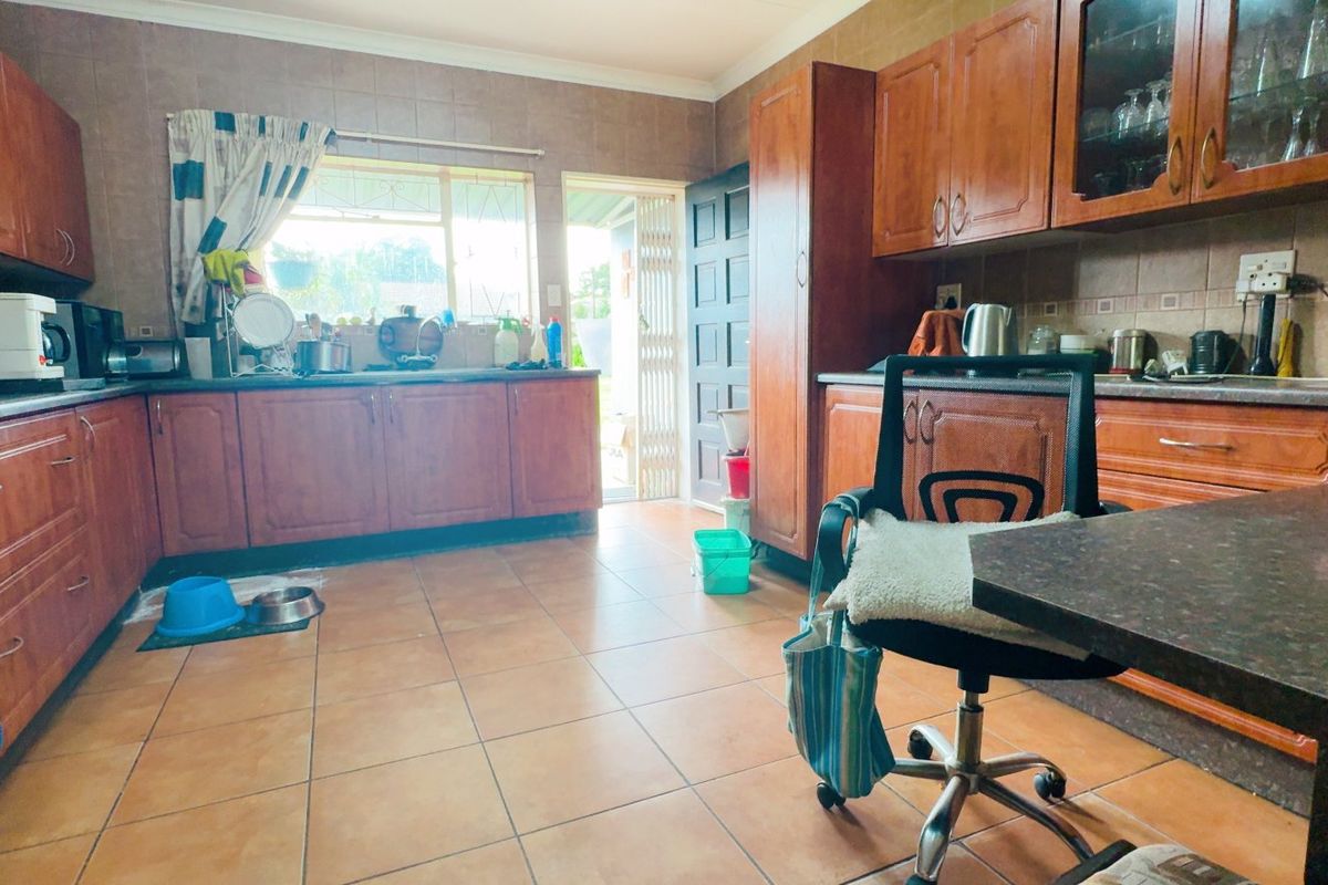 A functional kitchen featuring extensive wooden cabinetry, tiled flooring, and a tiled backsplash, offering a traditional layout with direct access to the exterior.