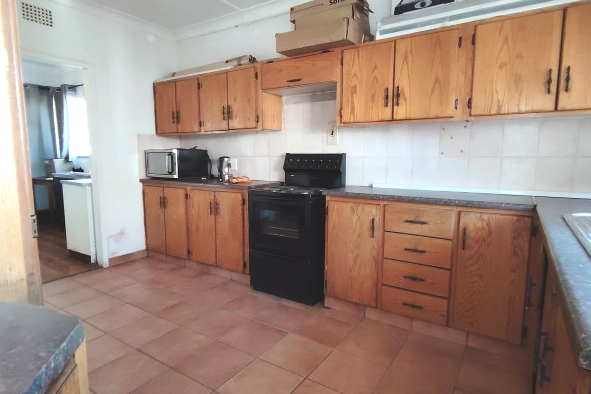 A dated kitchen featuring wooden cabinetry, tiled flooring, and a built-in oven, offering significant potential for a modern renovation.