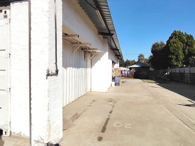 A view of the rear exterior area featuring a concrete driveway, external water tap, and precast boundary walling.