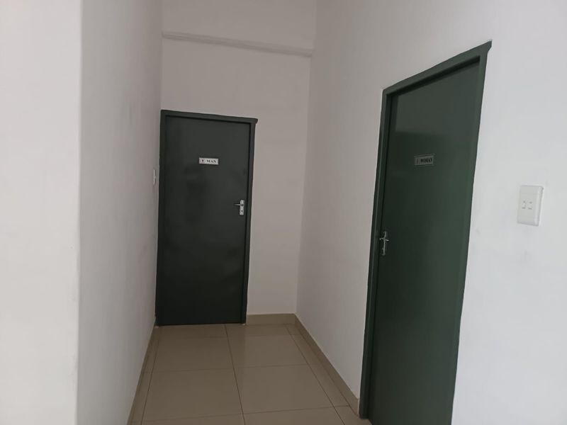 A functional hallway area featuring tiled flooring and access doors to separate male and female restroom facilities.
