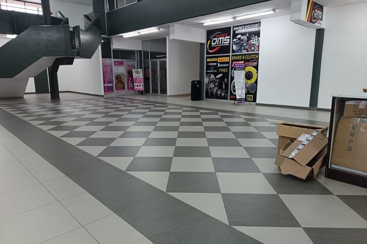 Spacious commercial entry area featuring a distinctive checkered tile floor, modern staircase, and glass storefront access points.