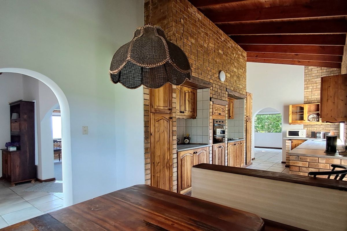 Rustic kitchen featuring exposed brick walls, timber beam ceilings, and built-in wooden cabinetry with arched architectural details connecting to adjacent living spaces.