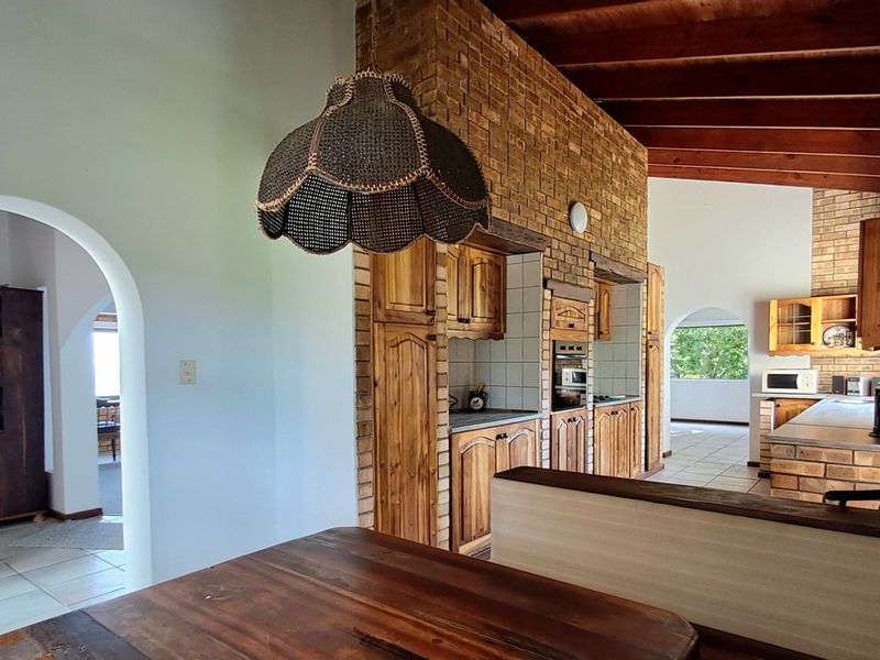Rustic kitchen featuring exposed brick walls, timber beam ceilings, and built-in wooden cabinetry with arched architectural details connecting to adjacent living spaces.