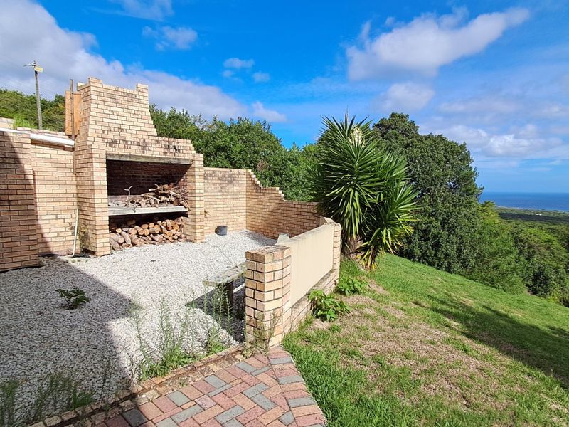 Outdoor patio area featuring a built-in brick braai, gravel flooring, and a low brick retaining wall with scenic landscape views.