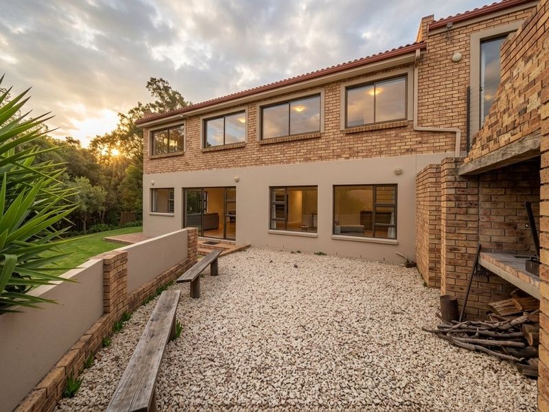 Rear exterior view of the farm property featuring a brick facade, gravel courtyard, and a built-in braai area overlooking the garden.