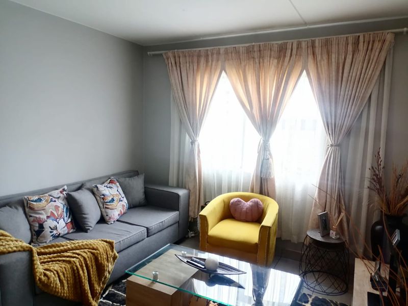 A cozy living room featuring neutral wall tones and large window treatments, providing a comfortable and functional space for relaxation.