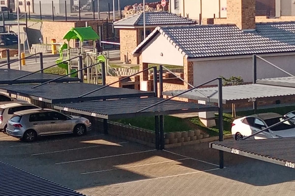 An elevated view of the apartment complex parking area featuring covered carports and paved driveways within a residential estate setting.