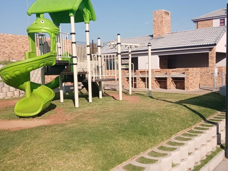Communal outdoor area featuring a children's playground and a brick-built braai facility within a well-maintained residential complex.
