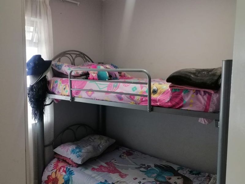 A compact bedroom featuring tiled flooring and a built-in cupboard, currently utilized as a children's room.