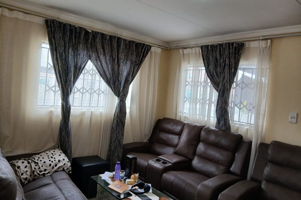 A living room featuring windows with security bars and curtain rails, providing a functional space for relaxation.