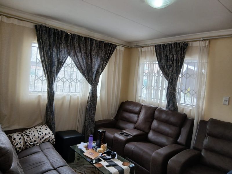A living room featuring windows with security bars and curtain rails, providing a functional space for relaxation.
