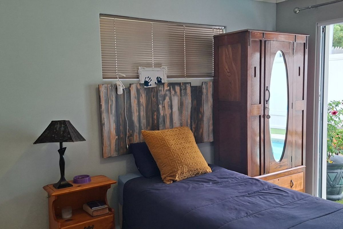 A bedroom featuring a sliding glass door with security gate, providing direct access to the outdoor area and natural light.