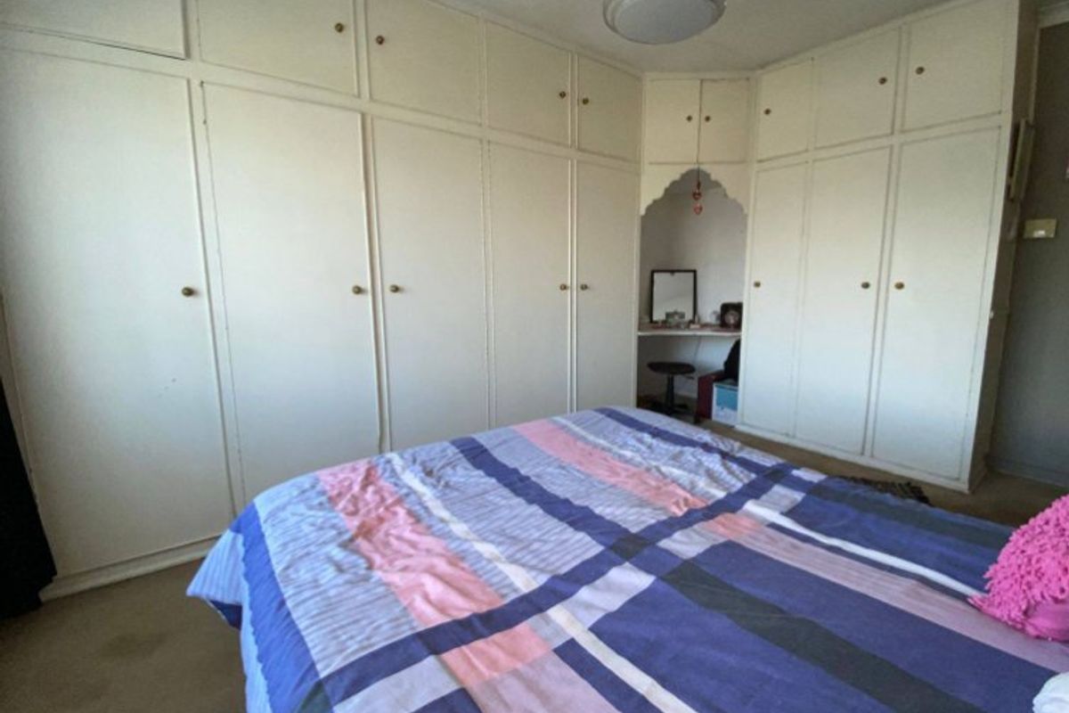 A bedroom featuring extensive floor-to-ceiling built-in cupboards and a small integrated vanity nook.