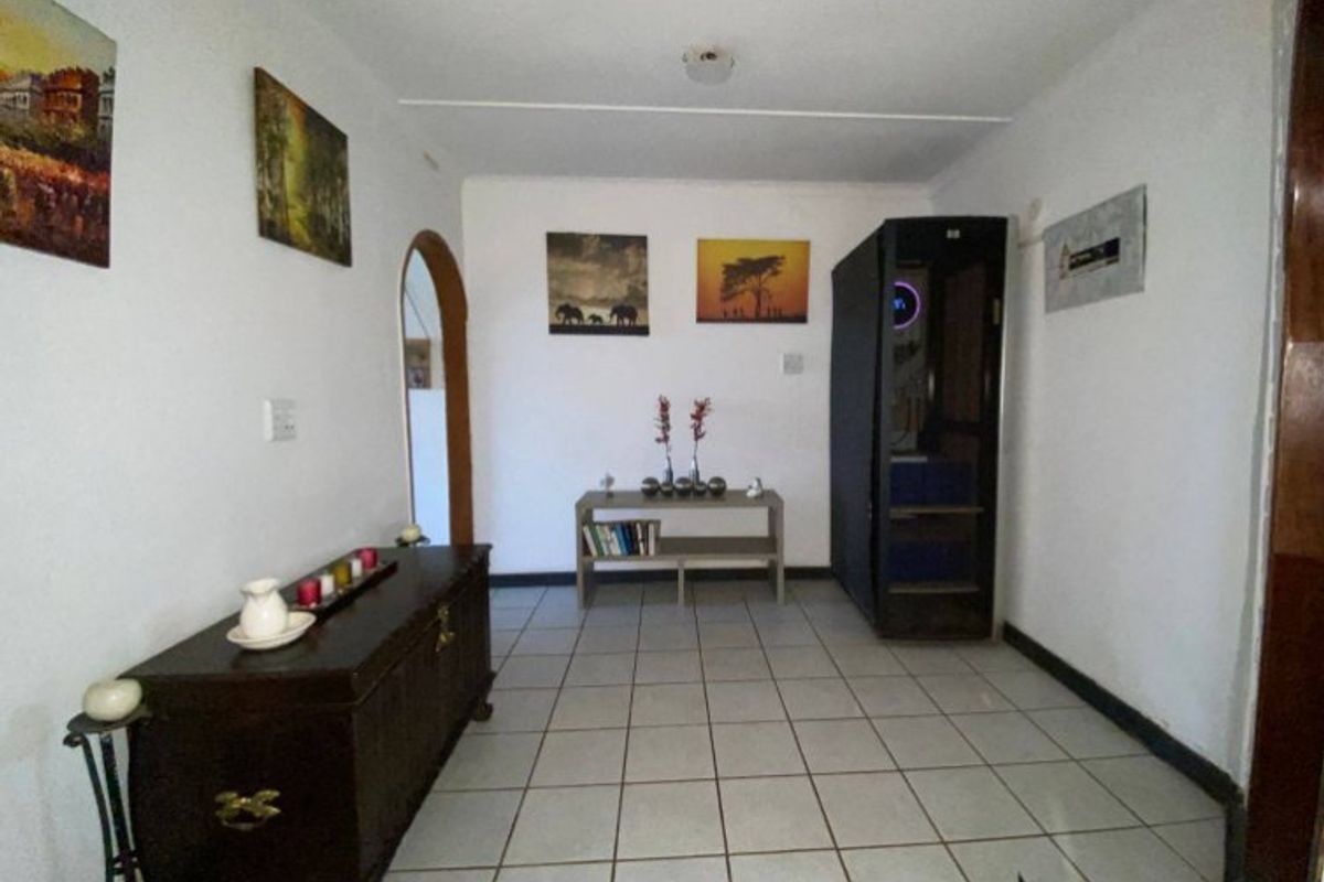 A living area featuring ceramic floor tiles and an arched doorway, providing a neutral base for potential interior design updates.