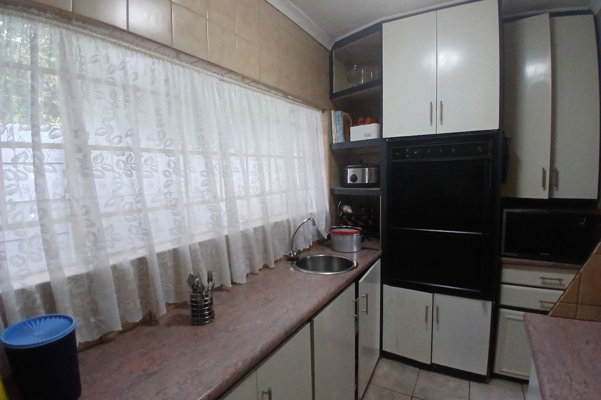A functional kitchen featuring built-in cabinetry, a laminate countertop with an integrated sink, and a built-in oven, showcasing a dated but practical layout.