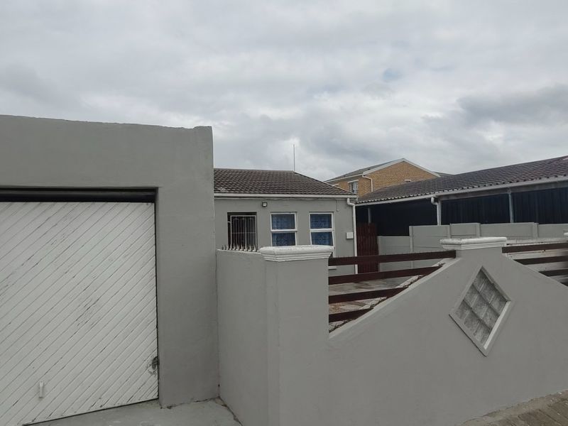 Front exterior view of the property featuring a single garage, boundary wall with decorative glass blocks, and a tiled roof structure.