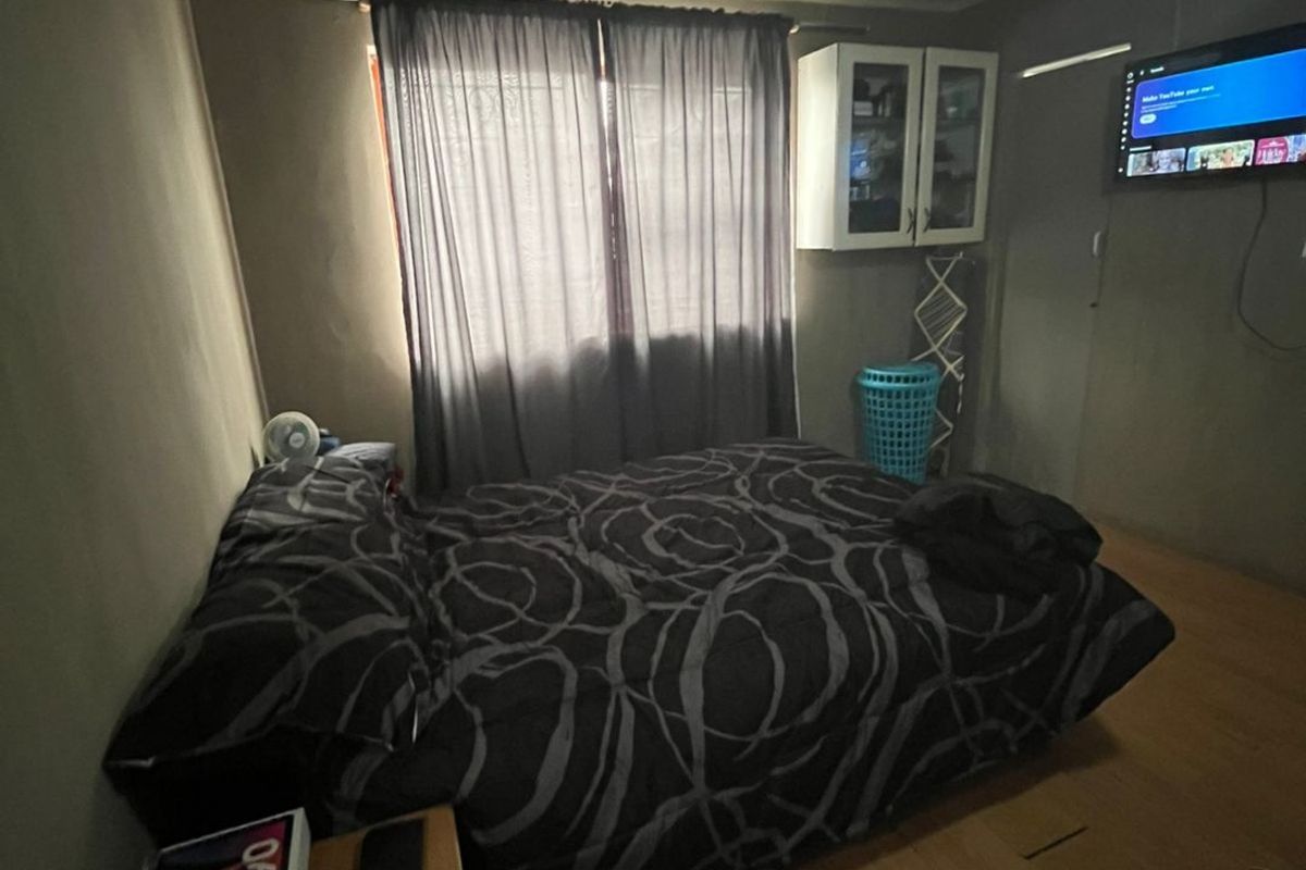 A bedroom featuring laminate flooring and wall-mounted storage cabinetry, requiring cosmetic updates to improve the overall finish and appeal.