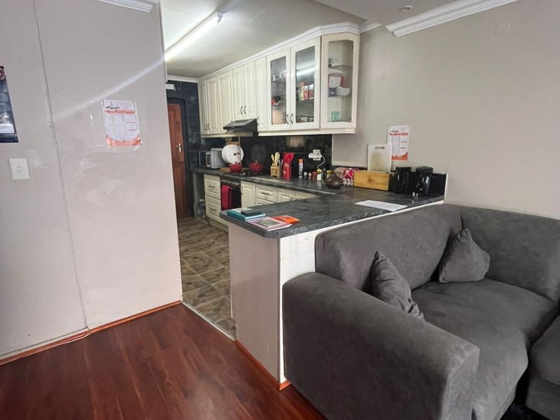 Open plan living area featuring a functional kitchen with built-in cabinetry and laminate flooring, seamlessly connected to the adjacent living space.