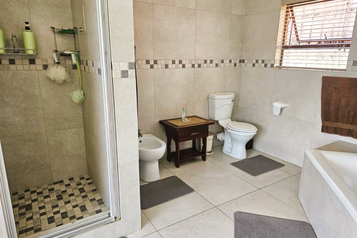 A well-maintained bathroom featuring a separate shower enclosure, bathtub, toilet, and bidet with neutral floor-to-ceiling tiling.