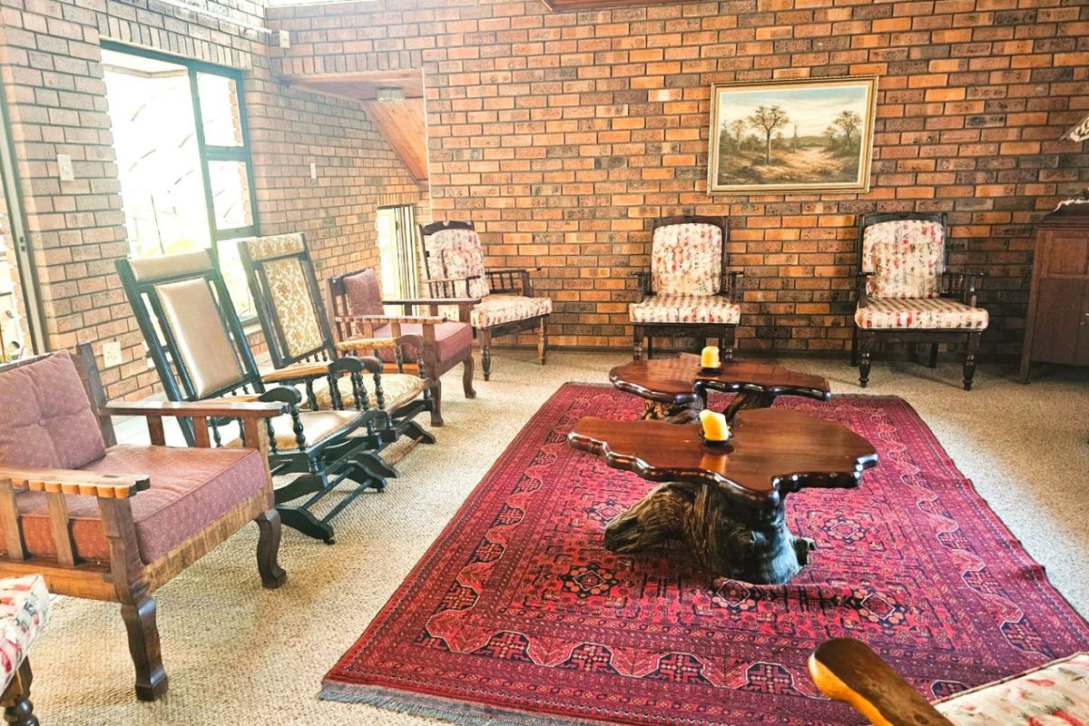 Spacious living room featuring exposed brick walls, timber ceiling details, and large windows providing natural light.