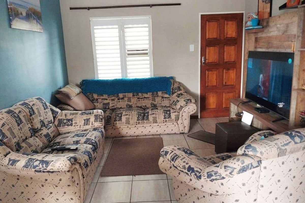 A living room featuring tiled flooring, a wooden door, and window shutters, providing a functional and comfortable space.