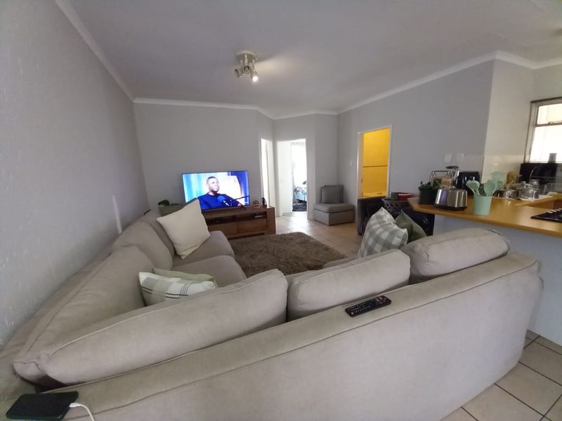 Open-plan living area featuring tiled flooring, a breakfast bar, and neutral wall finishes, creating a functional and connected space for daily living.