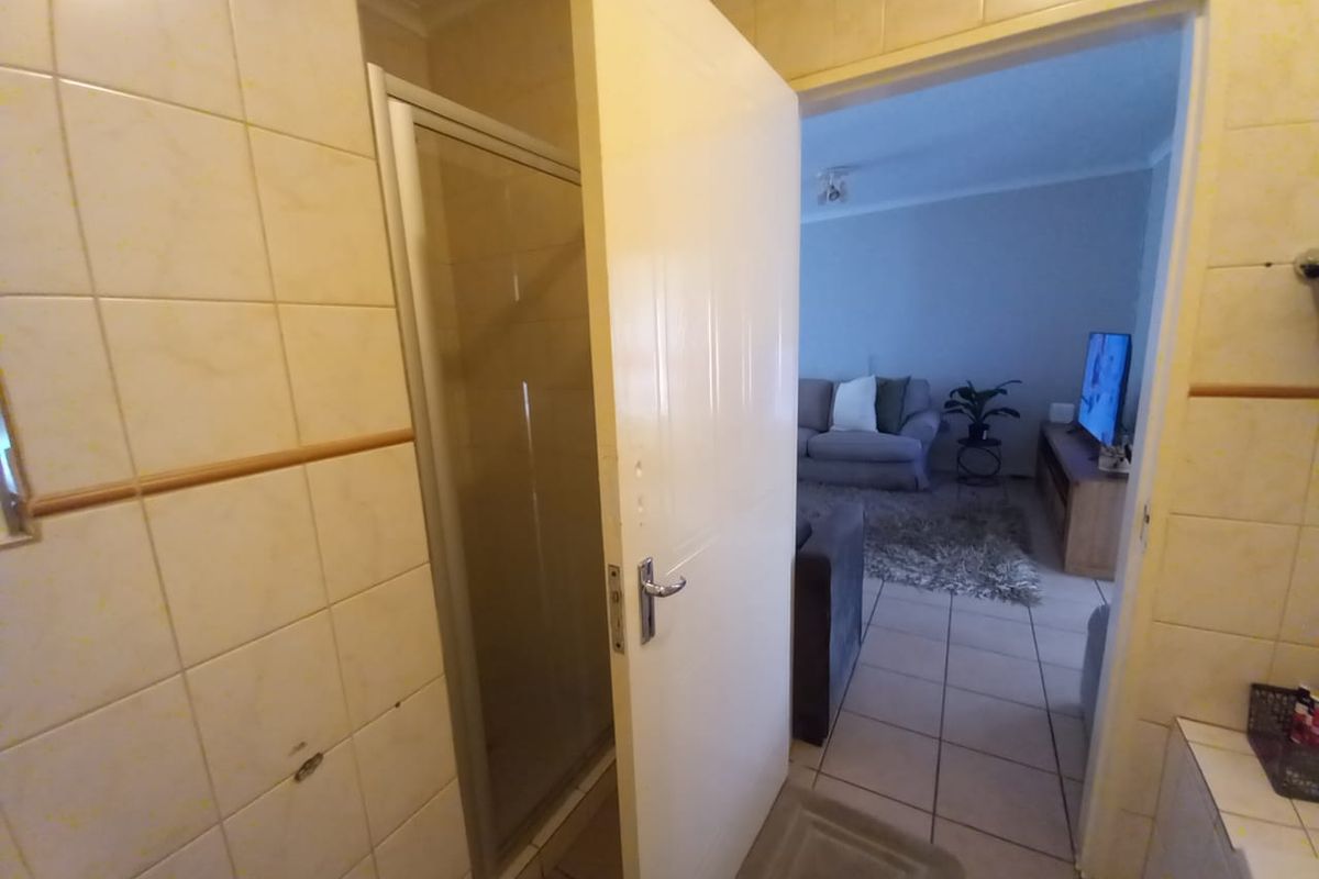 A bathroom featuring a shower enclosure with tiled walls and flooring, showing signs of wear and requiring cosmetic updates.