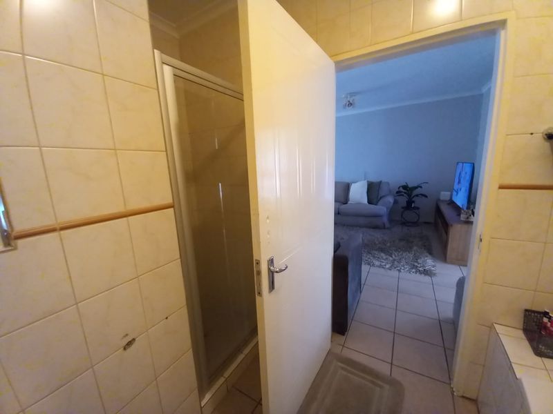 A bathroom featuring a shower enclosure with tiled walls and flooring, showing signs of wear and requiring cosmetic updates.