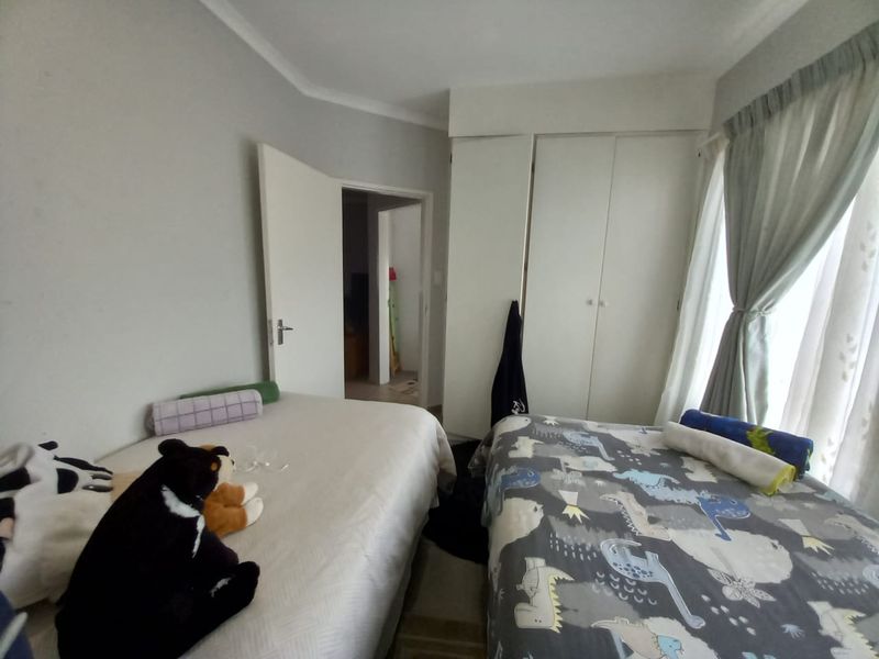 A bedroom featuring built-in cupboards and natural light through a window with curtain rails.