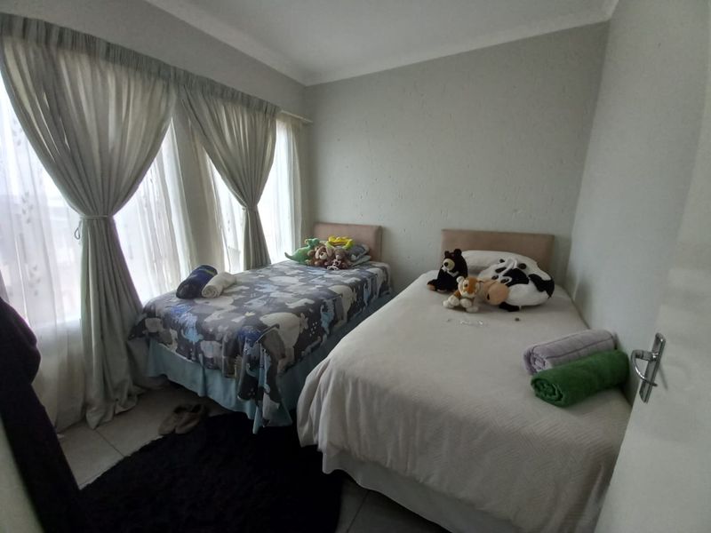 A functional bedroom featuring tiled flooring, coved ceilings, and large windows with curtain treatments, providing a comfortable space for rest.