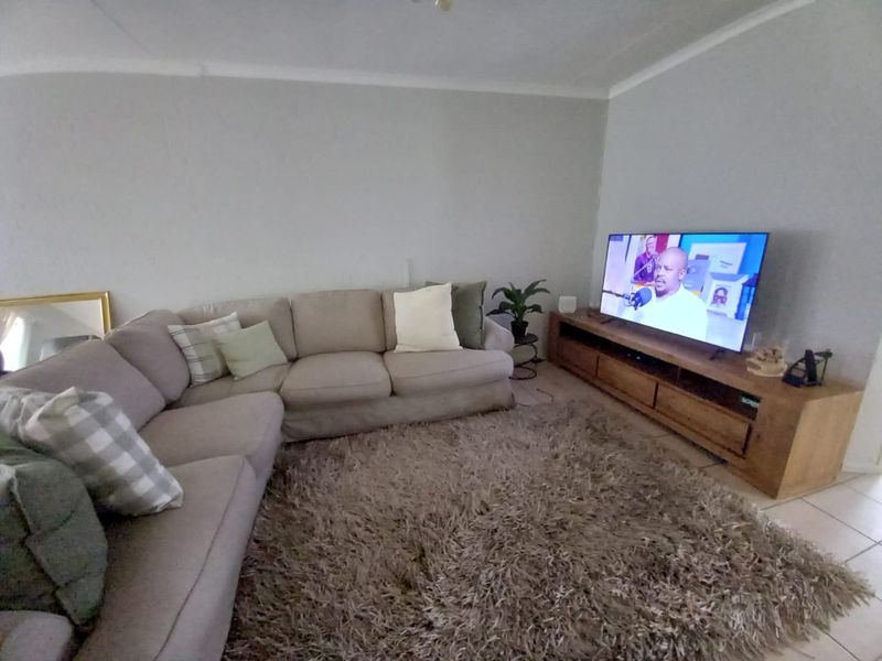 A comfortable living room featuring neutral tiled flooring and coved ceiling details, providing a functional and inviting space for relaxation.