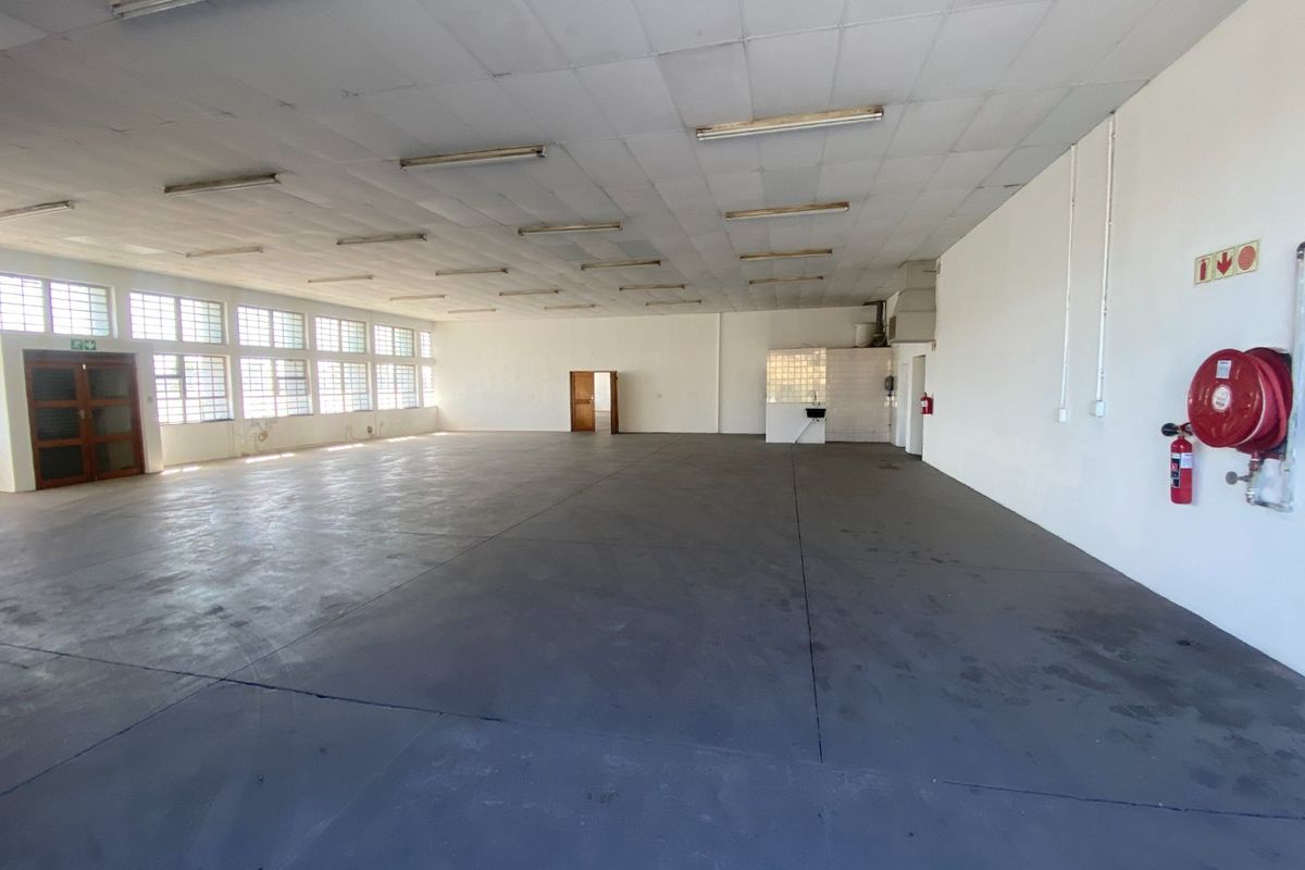Spacious industrial utility area featuring concrete flooring, suspended ceiling with fluorescent lighting, and integrated fire safety equipment.