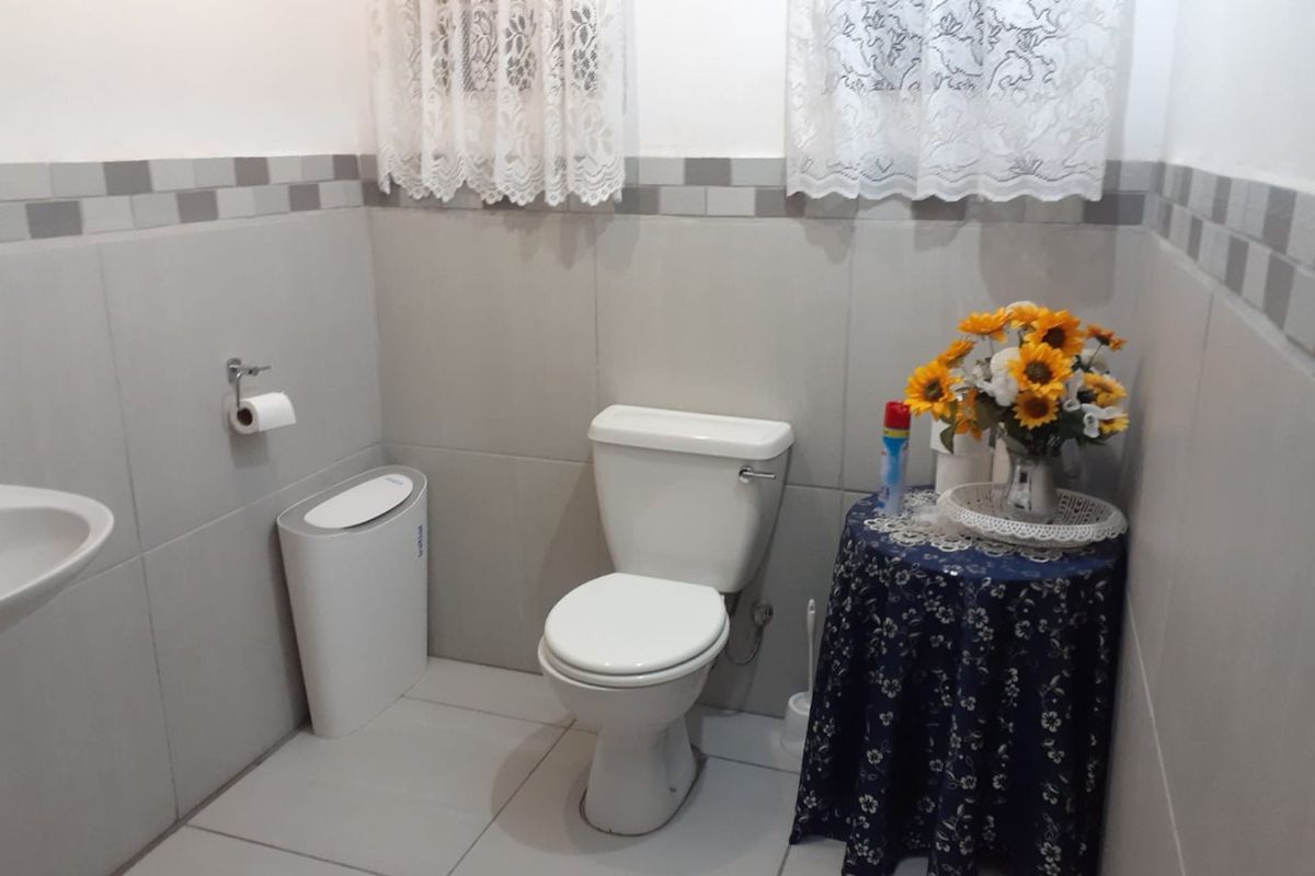 A functional bathroom featuring neutral ceramic wall and floor tiles with a decorative border, equipped with a standard white toilet.